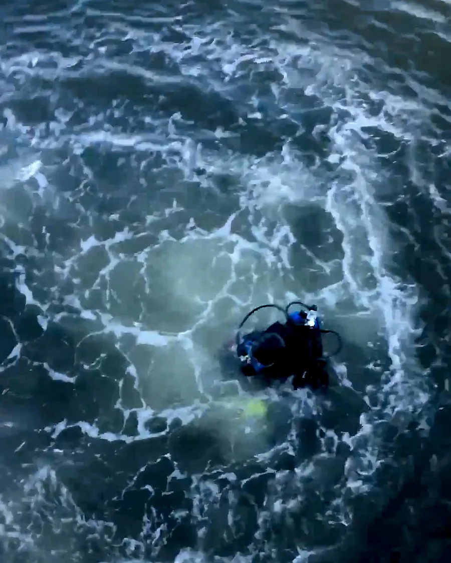 Diver working in the water near a dock and vessel